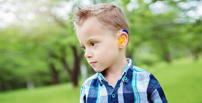 Young boy wearing hearing aid device