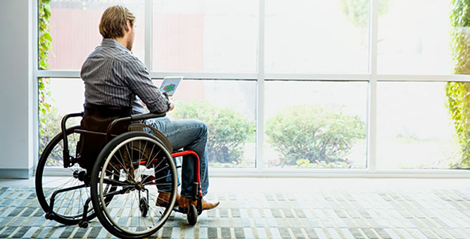 Man in wheelchair using tablet device.